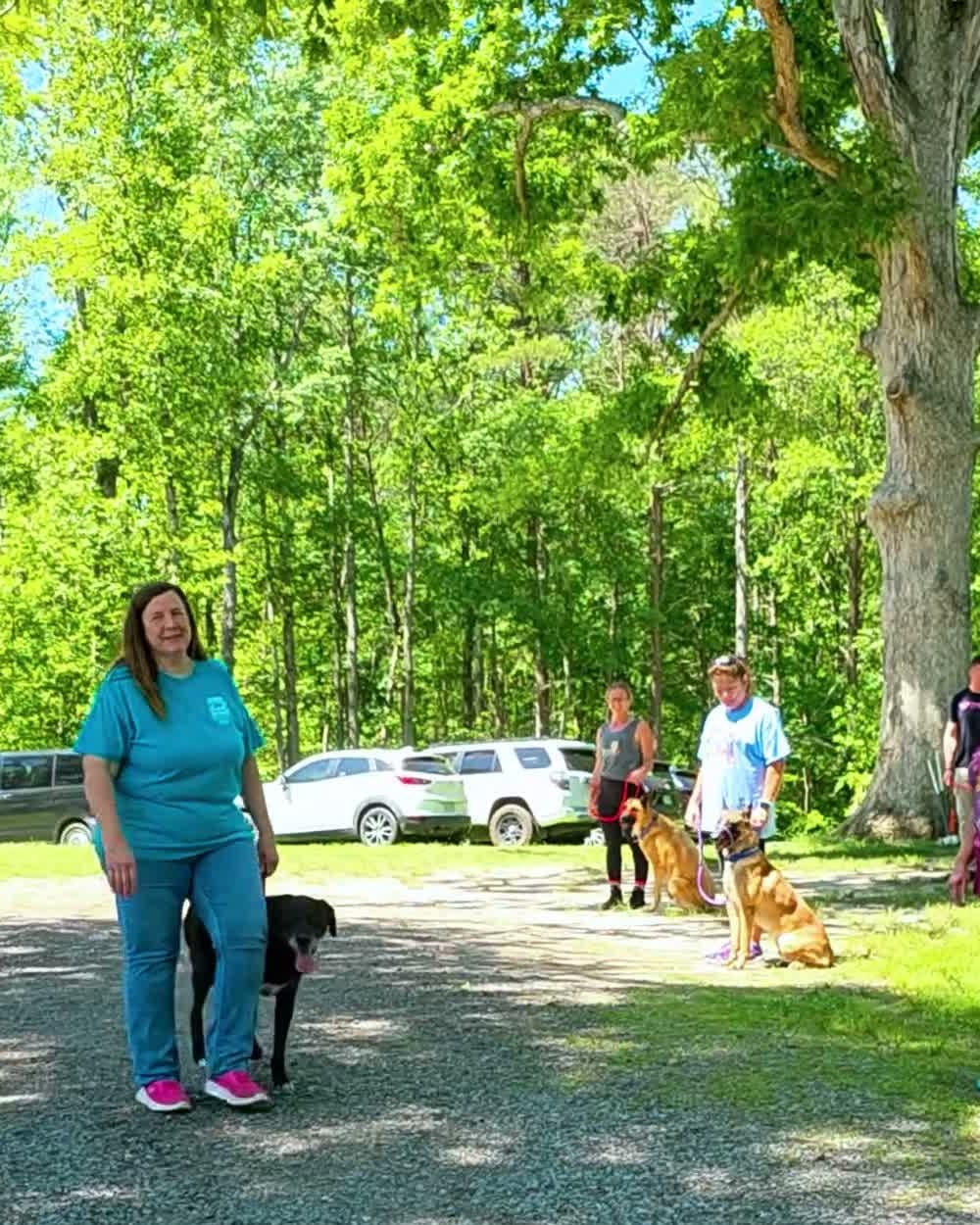 Handler holding her dog at heel during an outdoor group training class